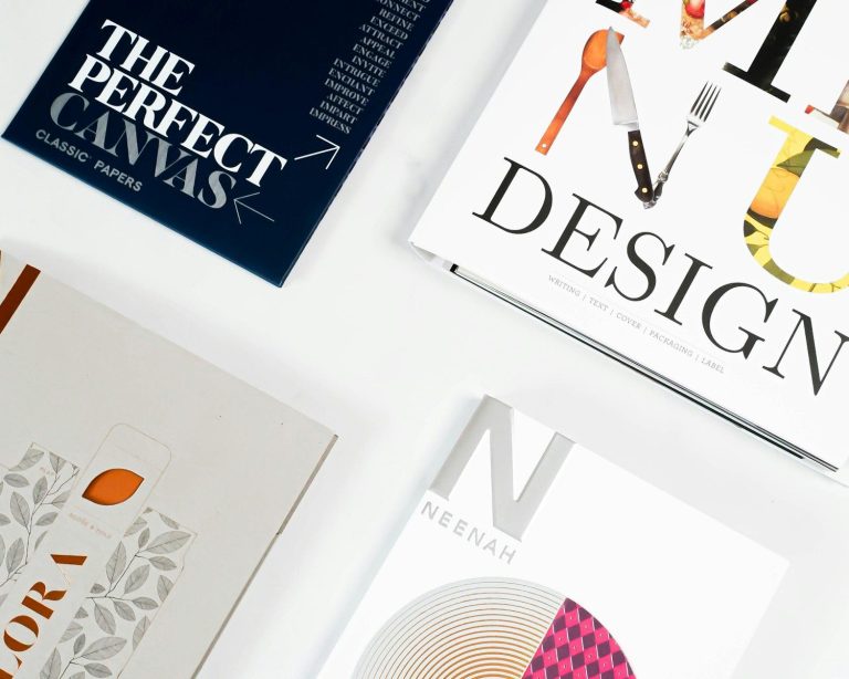 Four design books and paper sample brochures arranged on a white surface